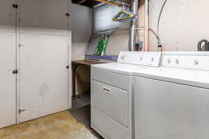 Laundry area with separate washer and dryer and concrete flooring