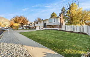 Raised ranch featuring brick siding, a chimney, an attached garage, and driveway