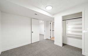 Unfurnished bedroom with carpet flooring, a closet, and a textured ceiling