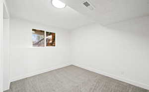 Carpeted spare room with baseboards and a textured ceiling