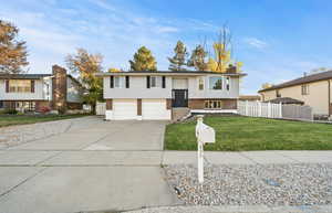 Split foyer home featuring brick siding, driveway, a chimney, and an attached garage