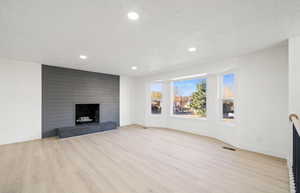 Unfurnished living room featuring recessed lighting, light wood-type flooring, and a fireplace