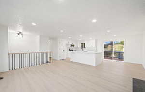Unfurnished living room featuring light wood-style flooring, recessed lighting, and a textured ceiling