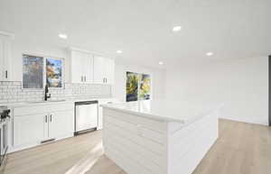 Kitchen featuring light wood finished floors, white cabinetry, appliances with stainless steel finishes, recessed lighting, and a kitchen island