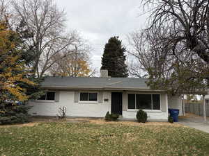 Ranch-style home with a front lawn, brick siding, roof with shingles, and a carport