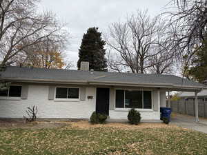 Single story home with a shingled roof, a porch, and brick siding