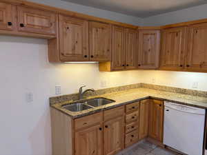 Kitchen featuring dishwasher, light stone counters, and light tile patterned floors