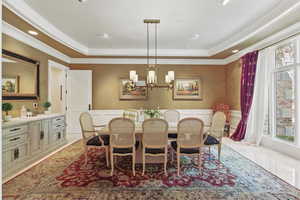 Dining room with a raised ceiling, a decorative wall, a wainscoted wall, recessed lighting, and a chandelier
