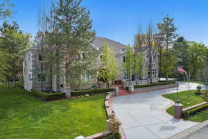 View of front of property with a front lawn, stone siding, and concrete driveway