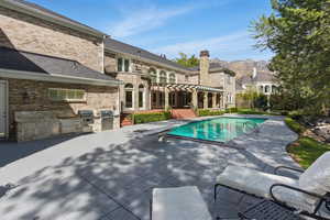 Outdoor pool with area for grilling, a pergola, a patio area, a diving board, and a balcony