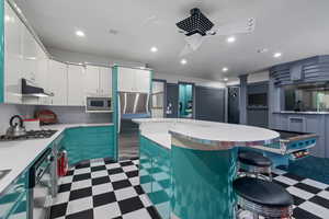 Kitchen with dark floors, a kitchen breakfast bar, white cabinetry, stainless steel appliances, and recessed lighting
