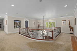 Corridor featuring an upstairs landing, light colored carpet, crown molding, and recessed lighting