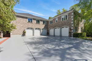 View of front of house featuring an attached garage, driveway, and brick siding