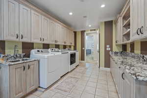 Laundry area with cabinet space, light tile patterned floors, recessed lighting, and washing machine and clothes dryer