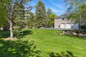 View of grassy yard featuring asphalt driveway and a garage