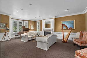 Living room with crown molding, carpet, a premium fireplace, a decorative wall, and recessed lighting