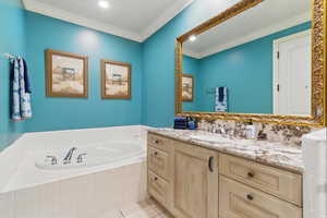 Bathroom featuring a bath, vanity, light tile patterned floors, and ornamental molding