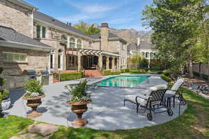 Back of property featuring a patio, area for grilling, a pergola, an outdoor pool, and a chimney