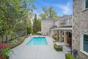 Swimming pool with a jacuzzi, a patio area, a balcony, and a diving board