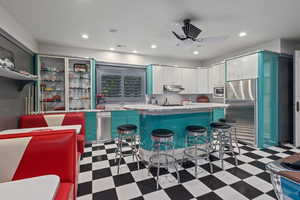 Kitchen featuring dark flooring, light countertops, a kitchen bar, open shelves, and appliances with stainless steel finishes