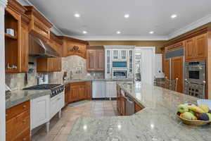 Kitchen with brown cabinetry, glass insert cabinets, recessed lighting, decorative backsplash, and light tile patterned floors