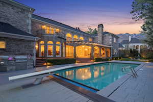 Swimming pool featuring a patio area, a diving board, an outdoor kitchen, and a balcony