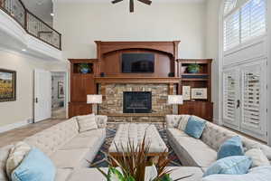 Tiled living room with a high ceiling, a stone fireplace, and a ceiling fan
