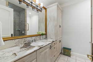 Full bathroom featuring light tile patterned flooring, vanity, ornamental molding, and a stall shower