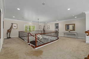 Hall with an upstairs landing, crown molding, light carpet, and recessed lighting