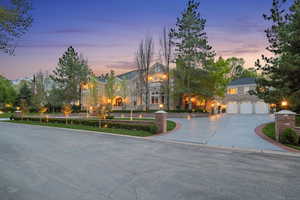View of front facade with curved driveway, stone siding, and a garage