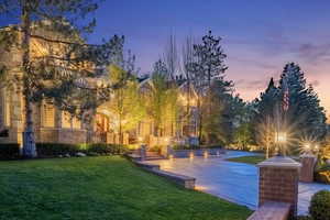 Pool at dusk featuring a lawn and a patio