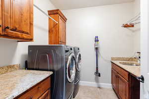 Washroom with light tile patterned flooring, cabinet space, and washing machine and clothes dryer