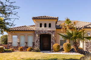 Mediterranean / spanish-style house featuring stone siding, stucco siding, a front yard, and a tile roof