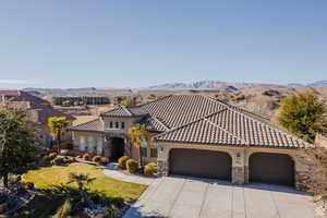 Mediterranean / spanish house with stone siding, a garage, a front lawn, and concrete driveway