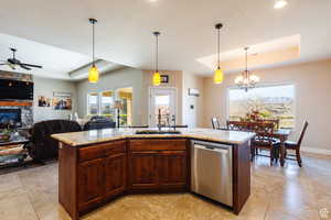 Kitchen with a tray ceiling, stainless steel dishwasher, and an island with sink