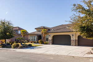 Mediterranean / spanish-style home with stucco siding, stone siding, driveway, a garage, and a tiled roof