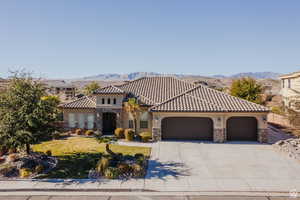 Mediterranean / spanish-style home with stone siding, a front yard, a garage, and a mountain view