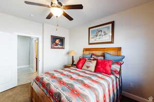 Carpeted bedroom featuring a ceiling fan and baseboards