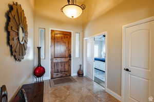 Foyer with a ceiling fan, inlaid floor details, and tile patterned floors