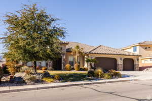 Mediterranean / spanish home with stone siding, stucco siding, driveway, a garage, and a front lawn