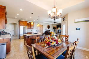 Dining area with arched walkways, recessed lighting, a ceiling fan, a tray ceiling, and light tile patterned flooring