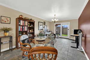 Dining space featuring ornamental molding, a chandelier, and a desk