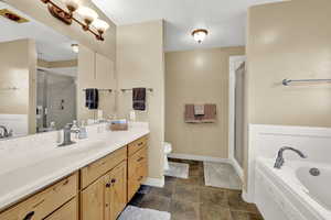 Bathroom featuring a garden tub, vanity, a stall shower, and a textured ceiling