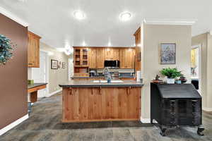 Kitchen with dark countertops, a peninsula, a textured ceiling, a kitchen breakfast bar, and appliances with stainless steel finishes