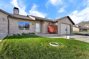 Ranch-style house with driveway, a front yard, brick siding, a garage, and roof with shingles
