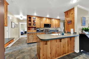 Kitchen featuring glass insert cabinets, stainless steel range with electric stovetop, a breakfast bar, dark countertops, and a peninsula