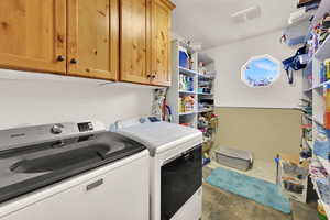 Washroom featuring independent washer and dryer, cabinet space, and dark tile patterned floors