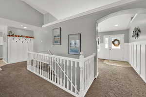 Hall featuring an upstairs landing, arched walkways, carpet flooring, recessed lighting, and high vaulted ceiling