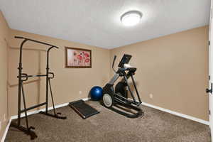Workout area featuring a textured ceiling and carpet flooring