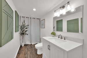 Full bath with dark wood-type flooring, vanity, a textured ceiling, shower / tub combo, and recessed lighting